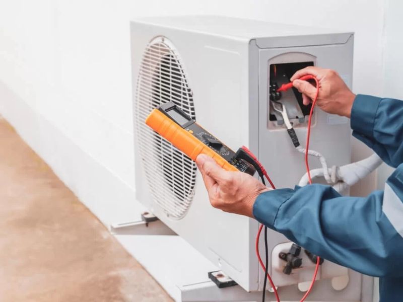 Technician cleaning an AC condenser coil
